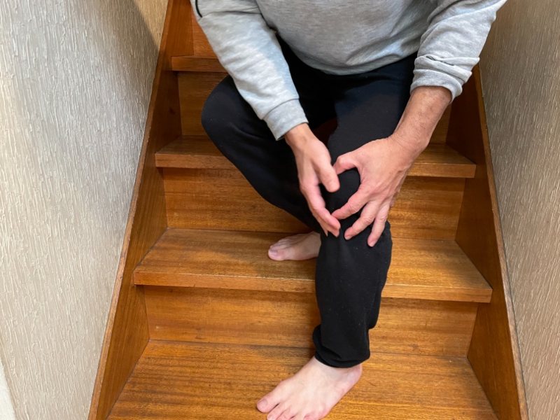 A person sitting on a staircase holding their knee