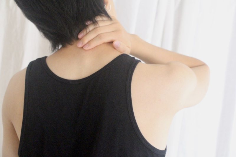 A person holding the back of their neck in pain