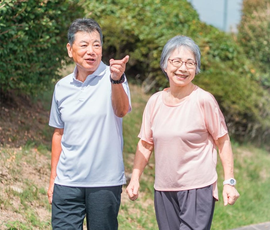 An older couple walking together outdoors, smiling